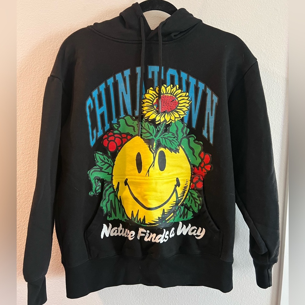 Black Chinatown Market hoodie with Nature Finds a Way Smiley Face design